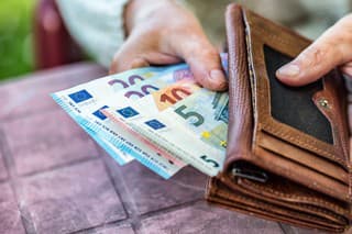 Pensioner woman holding in hands wallet with money.