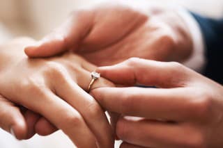 Cropped shot of an unrecognizable groom putting a diamond ring on his wife's finger during their wedding