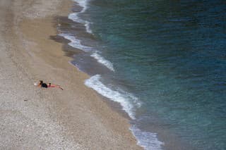 Dievča na na opustenej verejnej pláži na brehu Jadranského mora v chorvátskej Opatiji.