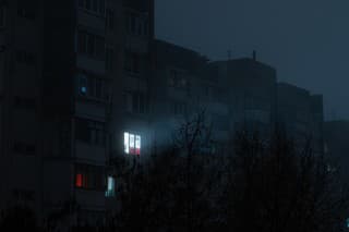 Light in one window in apartment multistorey building in fog during blackout of electricity in a residential area of Kyiv after russian shelling of power plants.