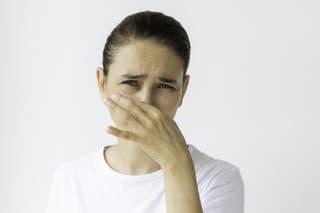 Caucasian female holding nose and is looking at camera. Representing bad smell and disgust.