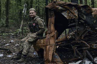 Ukrajinský vojak sedí na zhorenom vozidle na frontovej línii v Bachmute.