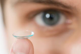 Close-up Of Young Man Holding Contact Lens On Finger