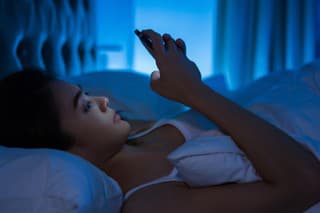 Asian women are using the smart phone on the bed before she sleeping at night. Mobile addict concept.