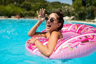 A beautiful girl in the pool on an inflatable donut is having fun on a hot summer day