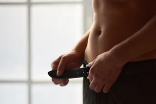 Man unbuckling belt. Attractive male body close up.