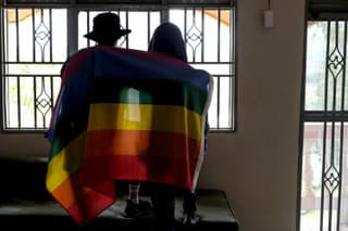 Na archívnej snímke z 25. marca 2023 homosexuálny pár pózuje s dúhovou vlajkou v Ugande.