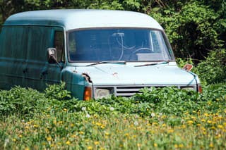 An old abandoned blue van in an open field