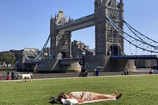 Žena sa opaľuje na tráve na Potters Field pri Tower Bridge v Londýne.