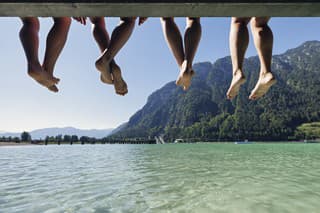 Mother and teenage kids enjoying summer vacations. They are sitting on pier on a lake Achensee in Austrian mountains. 
Sunny summer day.
Canon R5