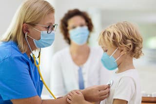 Pediatrician doctor examining sick child in face mask. Ill boy in health clinic for test and screening. Kids home treatment of virus. Coronavirus pandemic. Covid-19 outbreak. Patient coughing.