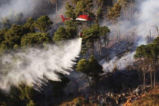 Hasičský vrtuľník vylieva vodu na lesný požiar na hore Altofonte neďaleko Palerma na talianskom ostrve Sicília.