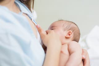 Mother breastfeeding a new born baby boy in a hospital room