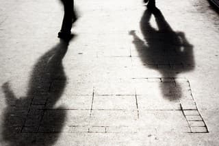 Shadow of two person on pattered sidewalk in black and white