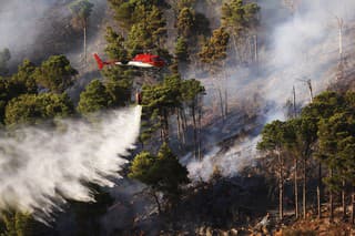 Hasičský vrtuľník vylieva vodu na lesný požiar na hore Altofonte neďaleko Palerma na talianskom ostrve Sicília