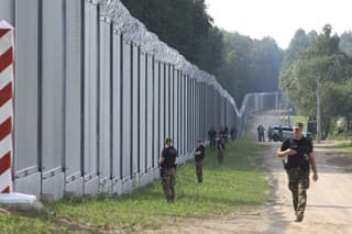 Na archívnej snímke z 30. júna 2022 poľskí pohraničníci hliadkujú pozdĺž nového železného múru na hraniciach medzi Poľskom a Bieloruskom.