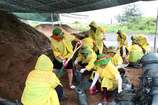 Dobrovoľníci napĺňajú vrecia pieskom počas príprav na tajfún Khanun v meste Čchangwon na juhovýchode Južnej Kórey