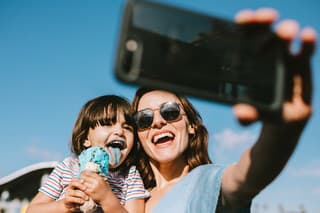 A mother takes a selfie of her and her daughter eating an ice cream cone at the Santa Monica Pier in Los Angeles, California.