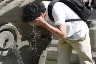 Muž sa chladí vo fontáne Barcaccia pred Španielskymi schodmi počas horúčav 22. augusta 2023 v Ríme. 