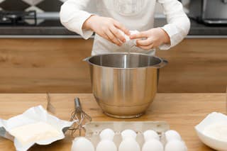 hands of No face child cracking, beating egg, preparing and mixing dough in modern kitchen. Little helping girl. Time without gadgets