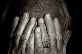 Black and white portrait of a senior man lost in the darkness.  Covering his eyes with his hands.You can find more photographs of this model in