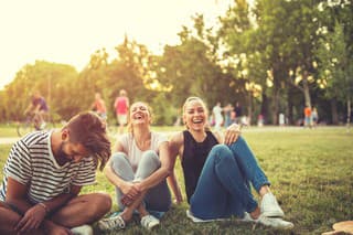 Three beautiful friends sitting in the park,laughing and having a great time