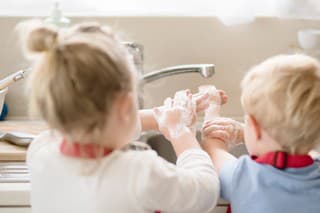Siblings washing their hands with soap