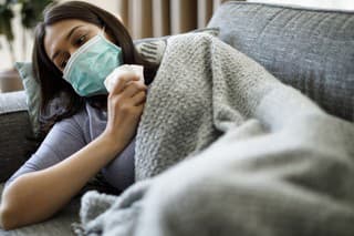 Sick woman with face protective mask lying in bed