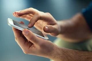 Male hands typing on smartphone.