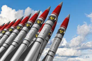 Row of heavy nuclear missiles against blue sky with clouds. See also: