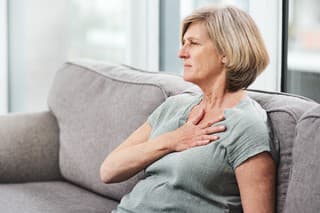 Shot of a senior woman suffering from chest pain while sitting on the sofa at home