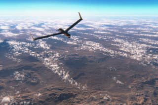 Military surveillance drone flying over rocky deserts.