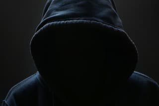 Unrecognizable person wearing hood against black background