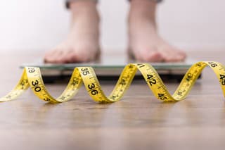 Women's legs on the scales, close-up of a measuring tape, the concept of losing weight, healthy lifestyle.
