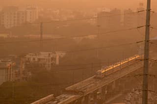 Evening shot of metro train on foggy delhi day. This is shot through electric wires that feed power to the railway lines. The metro is a power efficient public transport that will help solve the pollution and traffic congestion problems of Delhi Noida Gurgaon and other cities
