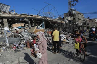 Palestínčania kráčajú medzi troskami zničenej budovy po izraelskom leteckom útoku na pásmo Gazy v Rafahu .