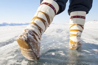 Mukluks on an Arctic Ice Road, Yellowknife, Northwest Territories, Canada.  Closeup of woman's feet while walking.  Ice, snow and sky, good copy space.