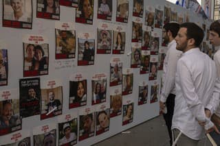 Izraelčania sa pozerajú na fotografie nezvestných Izraelčanov držaných v zajatí v Gaze 20. októbra 2023 v Tel Avive. 