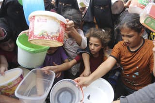 Palestínčania sa naťahujú za jedlom počas distribúcie potravín aj napriek pokračujúcemu izraelskému bombardovaniu v Rafahu, na juhu pásma Gazy v stredu 13. novembra 2023.