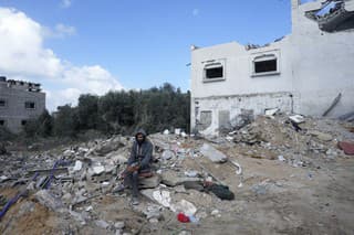Palestínčan sedí v troskách zničeného domu.