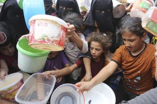 Palestínčania sa naťahujú za jedlom počas distribúcie potravín aj napriek pokračujúcemu izraelskému bombardovaniu v Rafahu, na juhu pásma Gazy v stredu 13. novembra 2023.