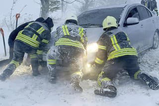 Ukrajinskí záchranári sa snažia odtlačiť auto, ktoré uviazlo na ceste počas snehovej víchrice v Odeskej oblasti.