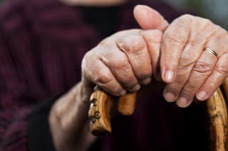 Close-up of senior woman's hands holding her walking sticks. Selective focus on hands and sticks.
