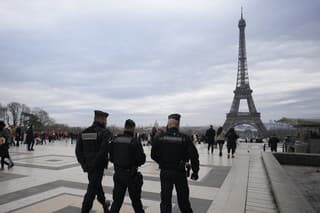 Policajti  hliadkujú neďaleko Eiffelovej veže v Paríži.