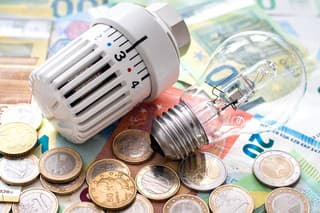 a heating valve and an old-fashioned lightbulb lie on top of euro bills and coins topic cost of energy supply