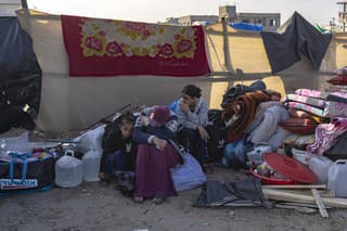 Obyvatelia Pásma Gazy, ktorí opustili v dôsledku vojny Izraela s militantným hnutím Hamas svoje domovy a presídlili sa na iné miesto v rámci enklávy, sedia pri stane v utečeneckom tábore v meste Rafah na juhu Pásma Gazy v pondelok 4. decembra 2023. 