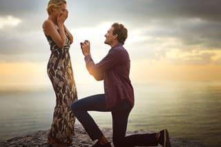 Shot of a young man proposing to his girlfriend at sunset