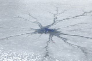 Eisloch,  verschneite rissige Eisfläche auf einem zugefrorenen See