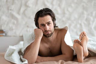 Frustrated young man and his wife lying in bed, stressed over family difficulties, having conflict, suffering from erectile dysfunction or lack of libido. Sexual problems, relationship crisis