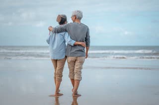 Senior couples walking on the beach at sunny day, plan life insurance with the concept of happy retirement.